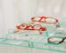 Stylish red eyeglasses displayed on a glass shelf in an eyewear store.
